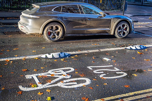 Tavistock Square, London, England - October 29th 2023:  Bike path marking in morning autumn sunlight with fallen leaves
