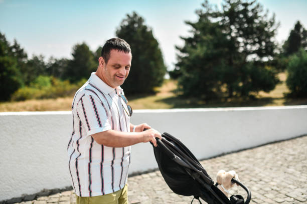 istock Caring Male With Down Syndrome Helping With Baby Stroller 1855296297