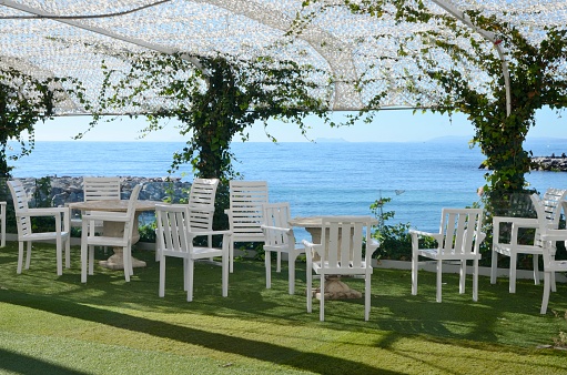 Marbella, Spain - December 10, 2023: Nobody at outdoor restaurant terrace with views to the Mediterranean sea at Banus Port, in Marbella, Spain.