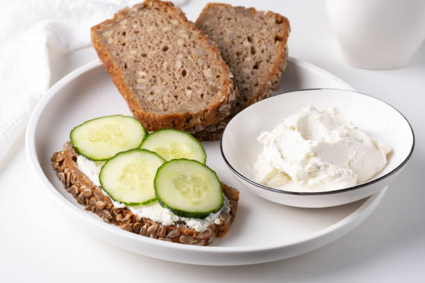 istock Rye bread with cream cheese and cucumbers on a white table. Whole grain rye bread with seeds 1855299012