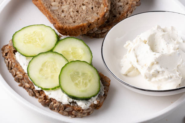 istock Rye bread with cream cheese and cucumbers on a white table. Whole grain rye bread with seeds 1855299016