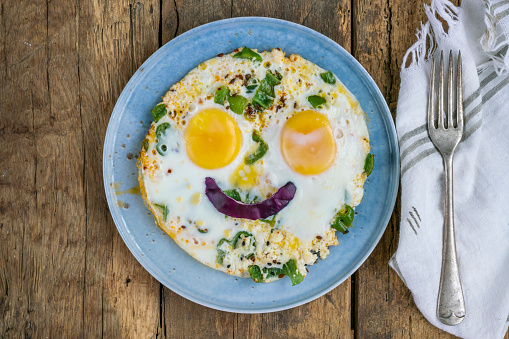 breakfast, sunny side up fried eggs with smiling face shape on wooden table for breakfast. food concept for children