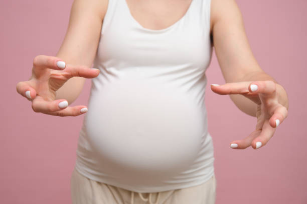 istock Pregnant woman angrily reaches her hands forward, studio pink background 1855309015