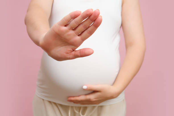 istock Pregnant woman showing stop gesture with hand, studio pink background 1855309562
