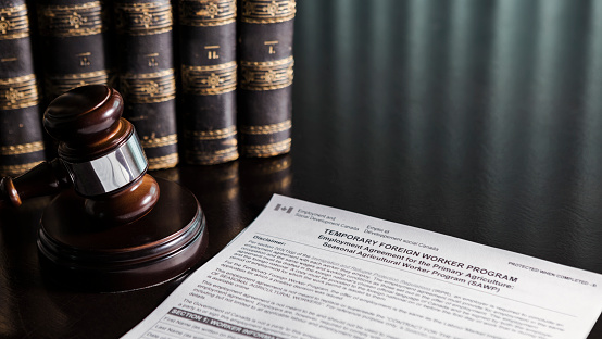 Close up of a Canada Temporary Foreign Worker application form with a gavel and books.