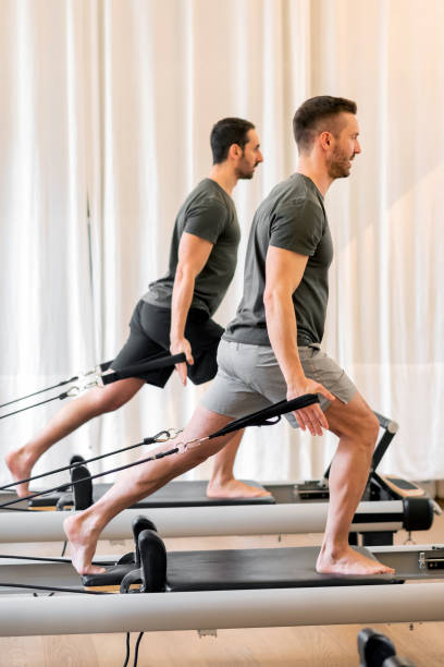 istock Fit men doing pilates exercises on reformer beds at gym 1855333511
