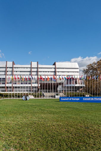 Strasbourg, France - November 11, 2023: Building of the Council of Europe in Strasbourg, Bas-Rhin, Alsace, France. Strasbourg is seat of the European Parliament. Flags of the member states in front of the building. Sunny november day.