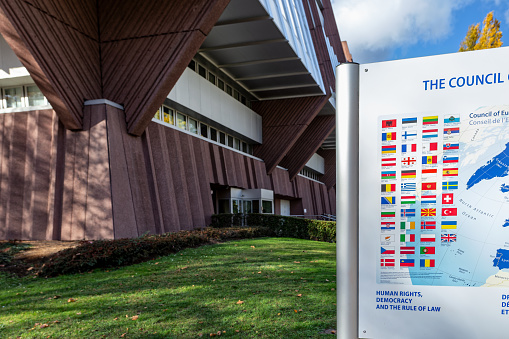 Strasbourg, France - November 11, 2023: Back of the Council of Europe in Strasbourg, Bas-Rhin, Alsace, France. Information board with the flags of the member states. Strasbourg is seat of the European Parliament. Sunny november day.
