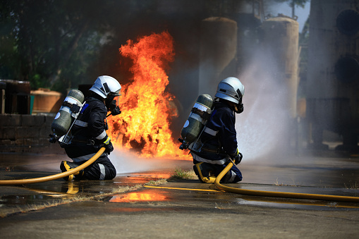 Firefighters using fire hose extinguishing burning fire