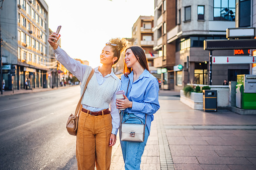 Young smiling female friends taking selfies in the city