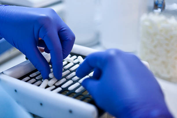 Packing white capsules in a sorting machine Packing white capsules in a sorting machine in a pharmaceutical laboratory, Spain sorter machine stock pictures, royalty-free photos & images