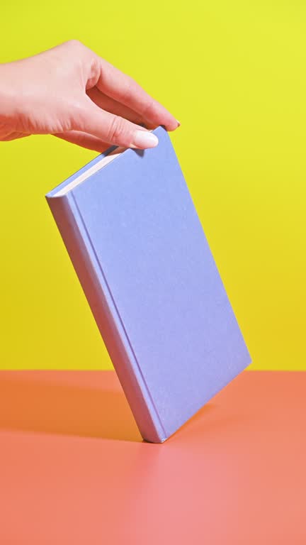 Vertical Stop Motion of Hand-Held Rotating Blue Book on Pastel Background