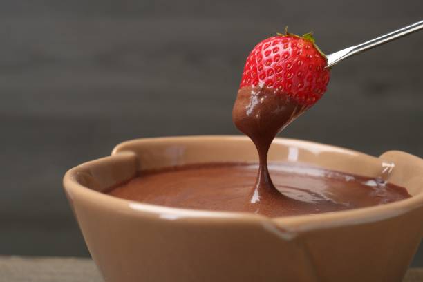 istock Strawberry with melted chocolate on fork above fondue, closeup. Space for text 1855454356