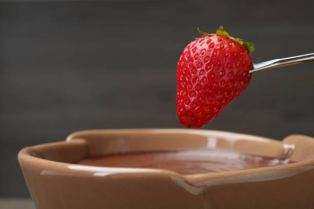 istock Strawberry on fork above fondue with melted chocolate, closeup. Space for text 1855458537