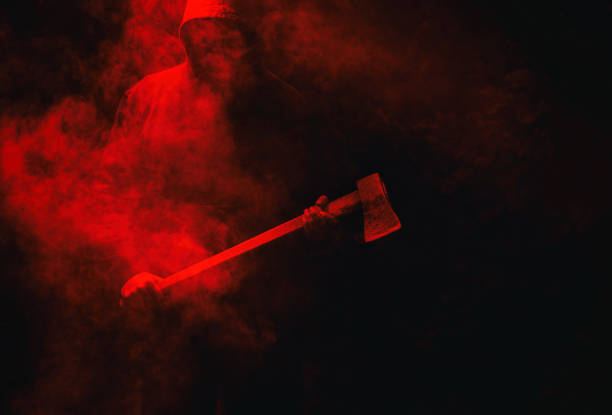 istock A maniac with an ax on a dark red background with smoke. 1855460112