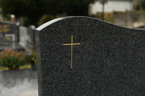 Cross on a marble slab on a grave in a cemetery