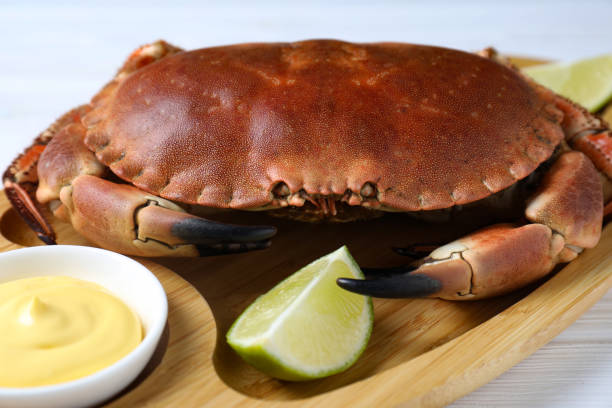 istock Delicious boiled crab served with lime and sauce on white table, closeup 1855491859