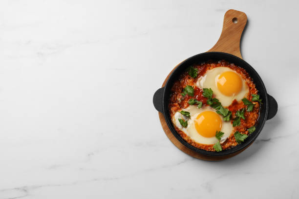 istock Delicious shakshuka in frying pan on white marble table, top view. Space for text 1855496116