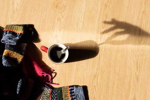 shadow silhouette of a hand and a cup of coffee in winter