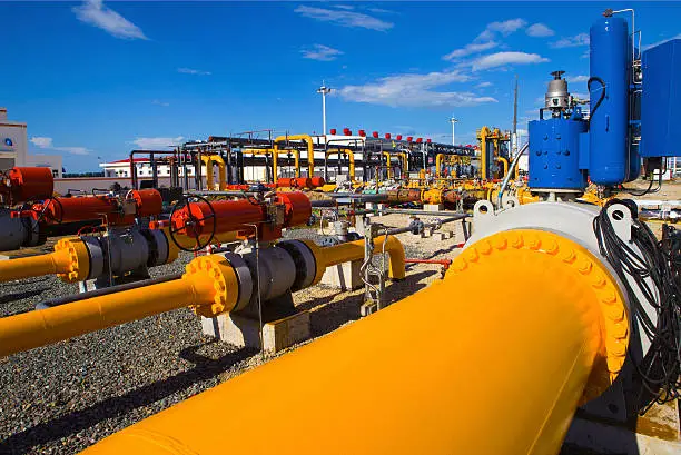 Photo of Yellow and orange pipe and valves at an industrial plant