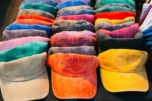A collection of colorful baseball caps for sale at the market.
