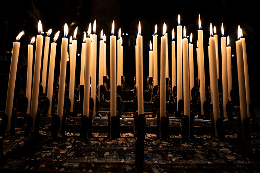 Many burning candles with an orange flame, in the interior of a church