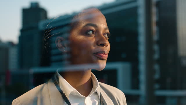 Businesswoman, thinking and glass in city by buildings, ambition and career planning in new apartment. African person, smile or idea by window, entrepreneurship or thought for job in urban cityscape
