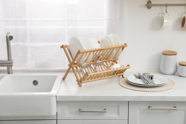 istock Drying rack with clean dishes on light marble countertop near sink in kitchen 1855555399