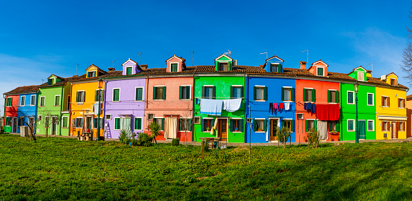 Burano, Italy- January 13, 2023: Panoramic of the streets of Burano island in Venice, colorful city with water canals and boats in the houses, during a sunny summer day.
