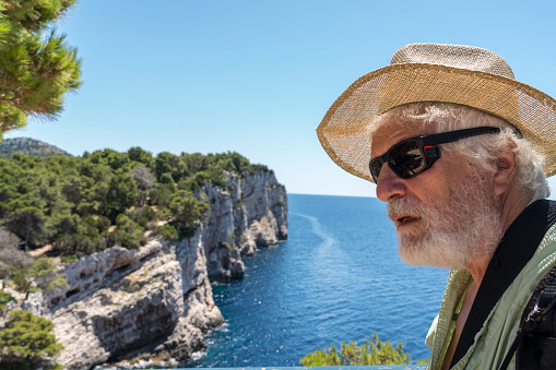 Portrait of a senior men enjoying the view of cliffs of Telascica, national park in Dugi otok island, Kornati islands in background. Croatia