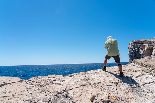 Senior men walking on smooth stone surface against clear blue sky in Telascica, national park in Dugi otok island, Croatia