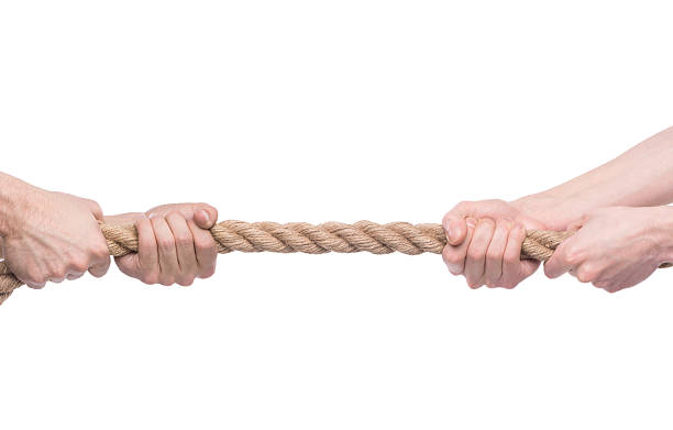 Two men's hands pulling opposite ends of rope Two people pulling a rope in opposite direction isolated on white background. rivalry photos stock pictures, royalty-free photos & images