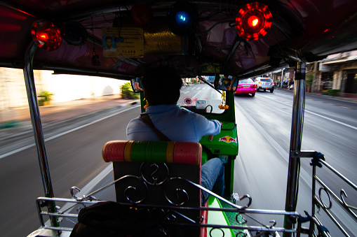 A colorful and loud Tuk Tuk races through the busy streets adorned with vibrant lights and designs. Bangkok, Thailand