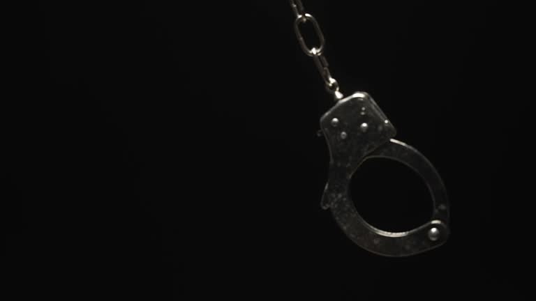 Close-up of Handcuff Swinging in Black Background