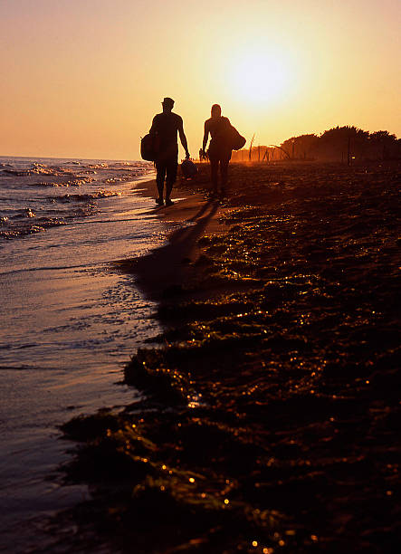 pareja caminando en la playa al atardecer - mer people fotografías e imágenes de stock