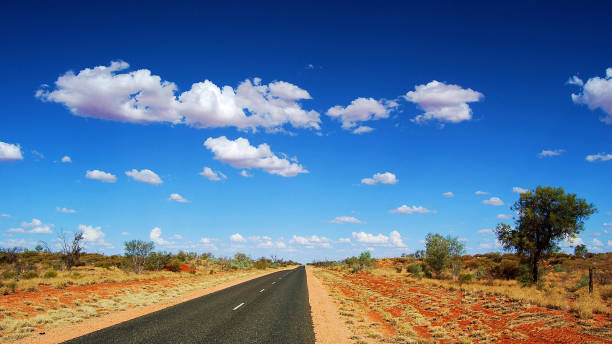 A long stretch of road with vegetation at Outback, Australia stock photo