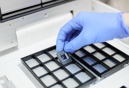 A researcher putting a chip in the PCR system for digital PCR performance