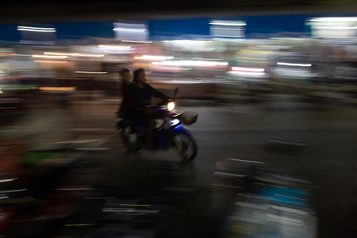 A long exposure of a motorbike racing through the busy traffic in the small city of Mae Klong, Thailand