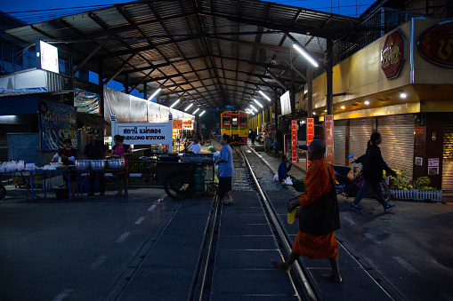 A monk walks past the end station for the famous rail road market. The Rom Hub Market is famous for an active railroad passing directly through the busy outdoor market space in Mae Klong, Thailand