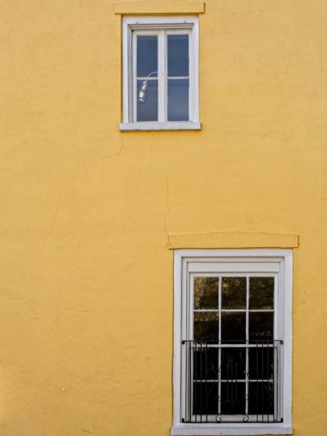 istock Pattern of white windows on yellow stucco wall 1855631762