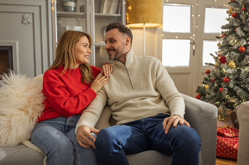 Young couple sitting on sofa for Christmas and talking.