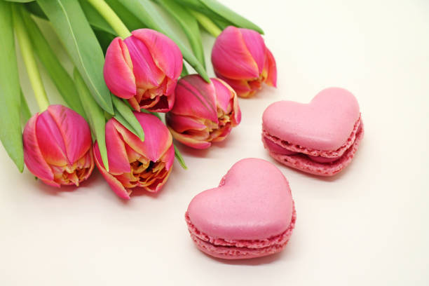 Bouquet of fresh tulips with pink macroons close-up. stock photo