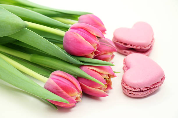 Bouquet of fresh tulips with pink macroons close-up. stock photo