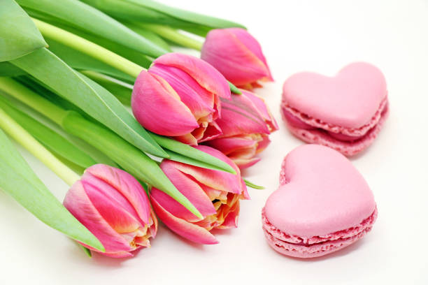 Bouquet of fresh tulips with pink macroons close-up. stock photo