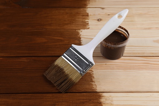 Wood stain in plastic container and brush on wooden surface