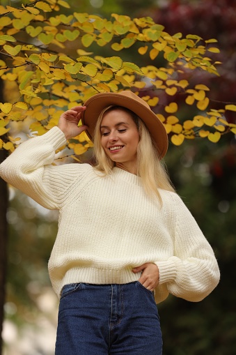 Portrait of happy woman wearing warm sweater in autumn park