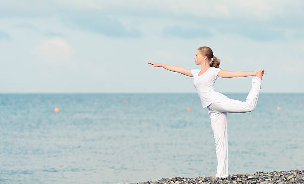 istock woman in white doing yoga on  beach 185567635