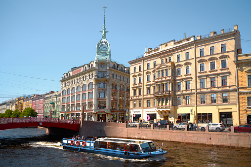 Cityscape of the street and Griboyedov water canal with a pleasure boat, old residential multi-colored buildings in the historical center of St. Petersburg, Russia.