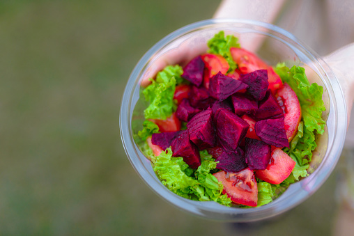 plastic container without people with lettuce, beets, and tomatoes with copy space