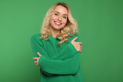 Happy woman in stylish warm sweater on green background